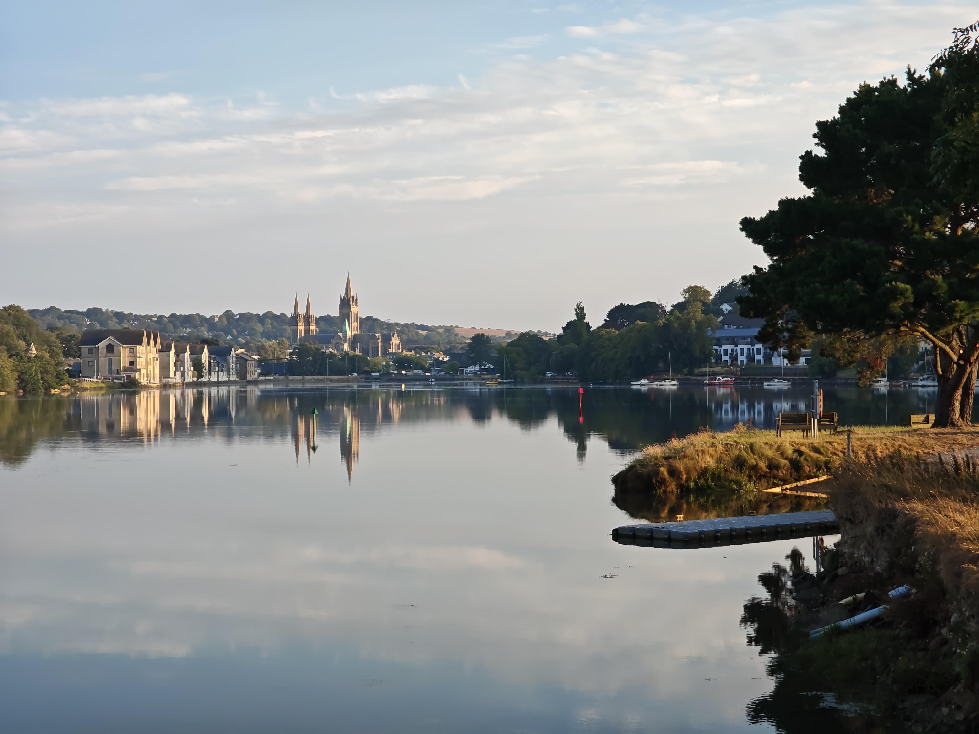 Truro Cathedral seen across the river from Boscawen Park, framed by riverside buildings and trees