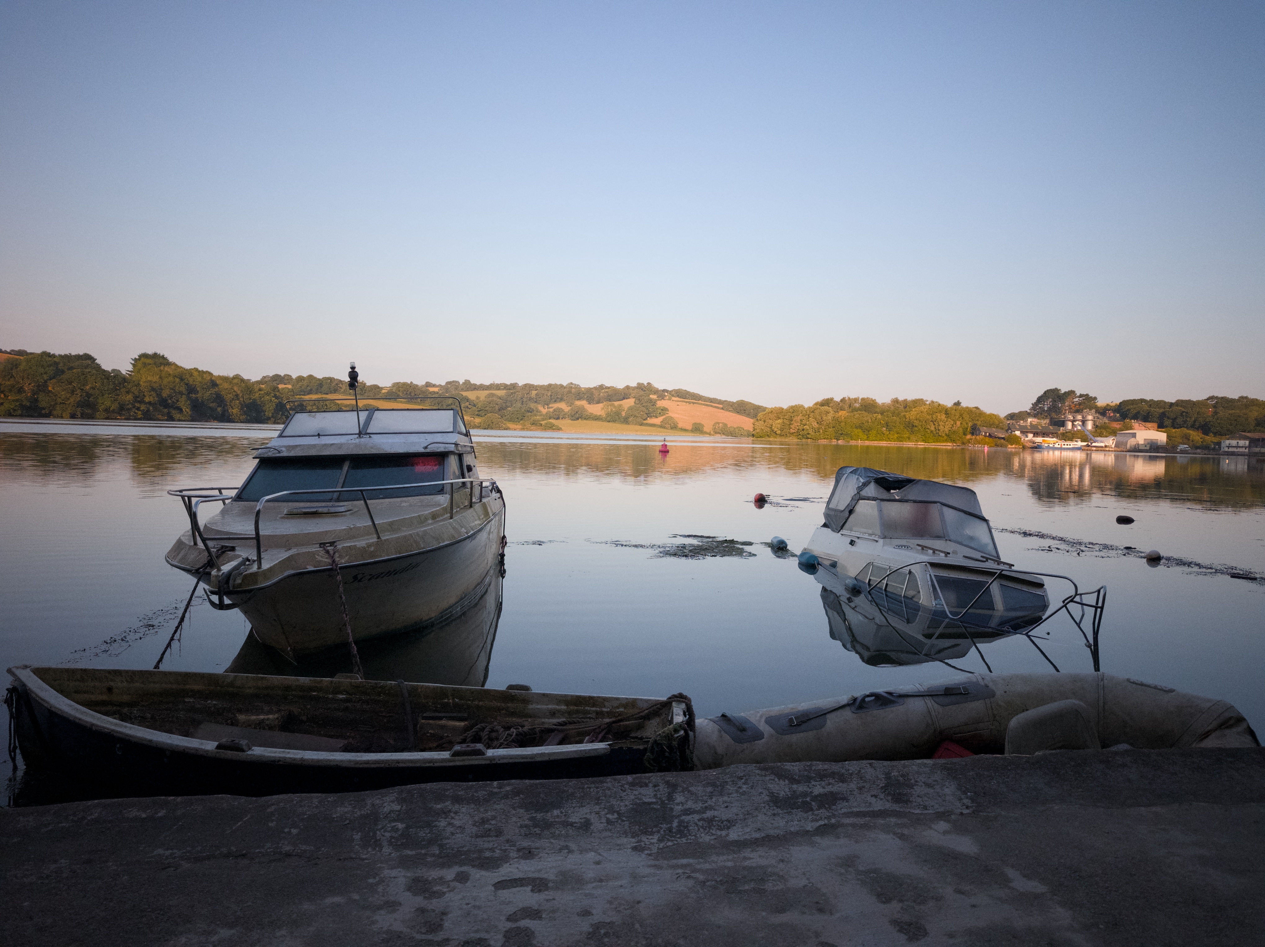 Three small boats moored on still water at Boscawen Park, reflections visible